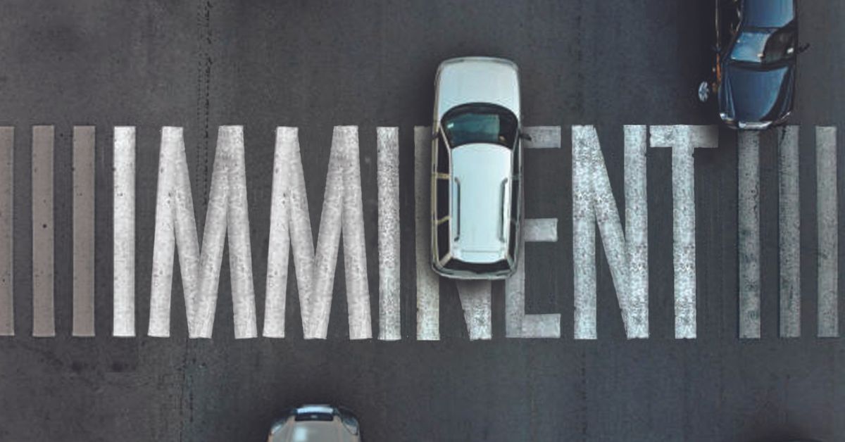 cars driving over a pedestrian crossing that has the word IMMINENT on it